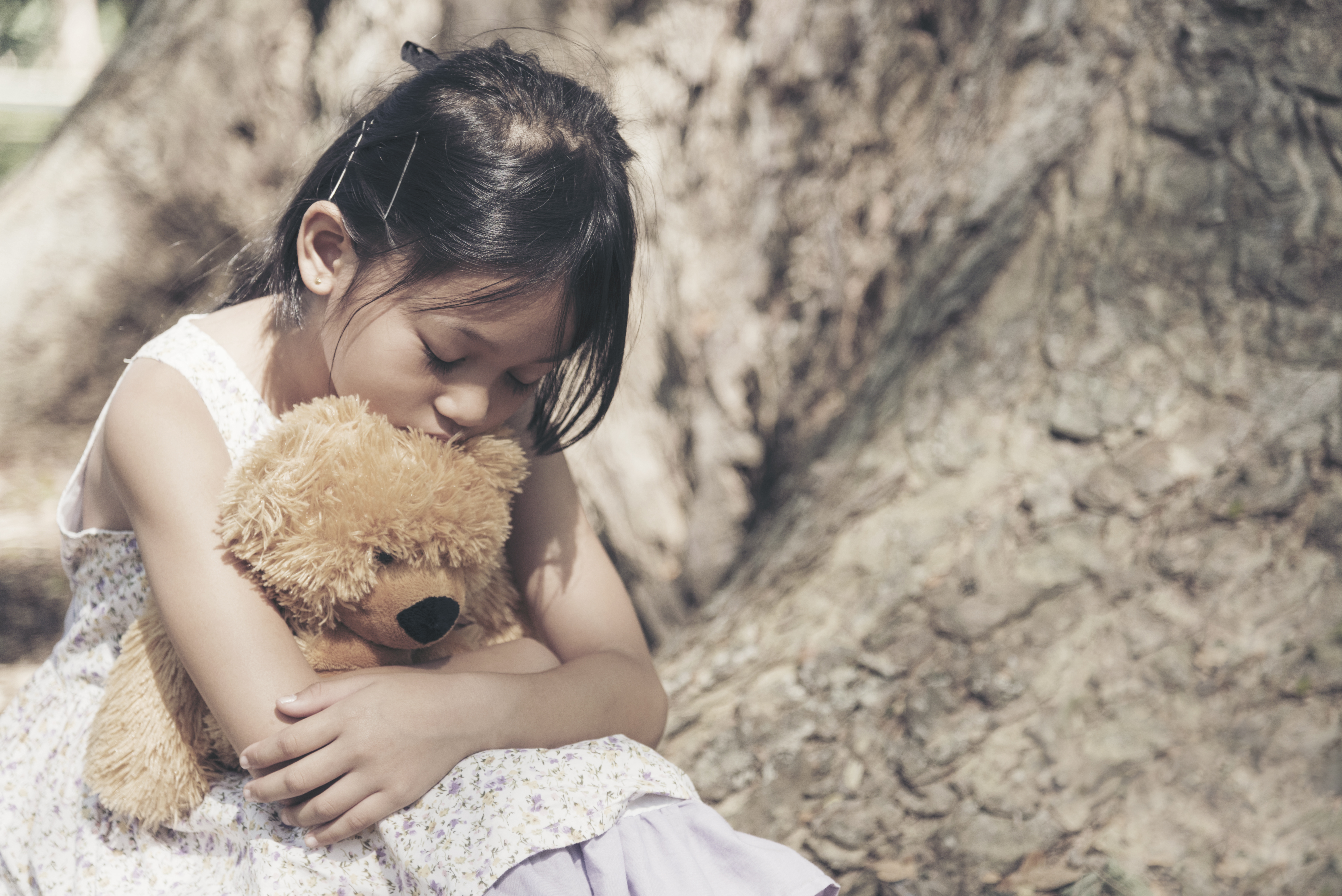 Trauma affects beliefs.  Girl holding a teddy bear.